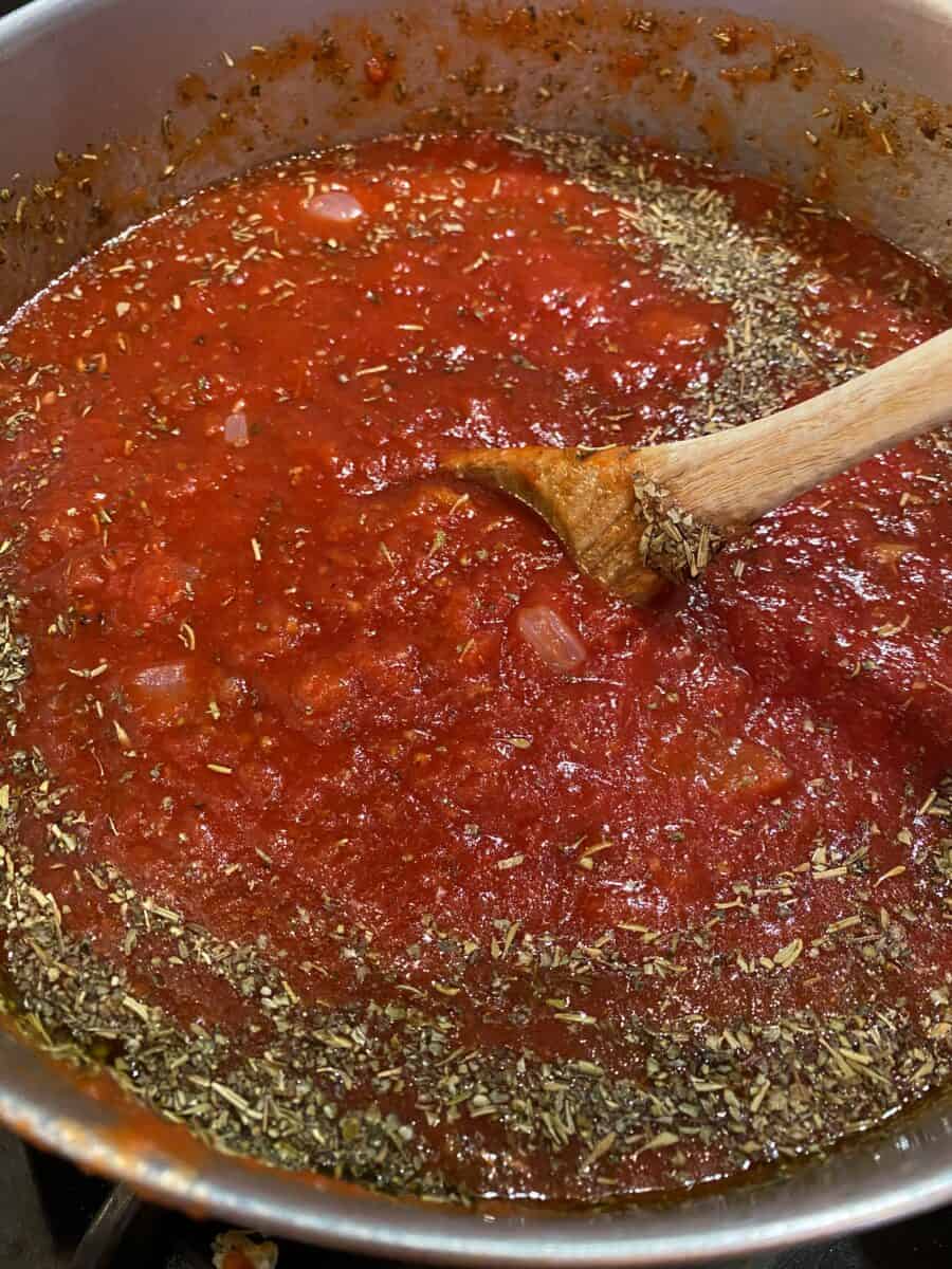 Red sauce with Italian seasoning in a large stock pot on the stove. 