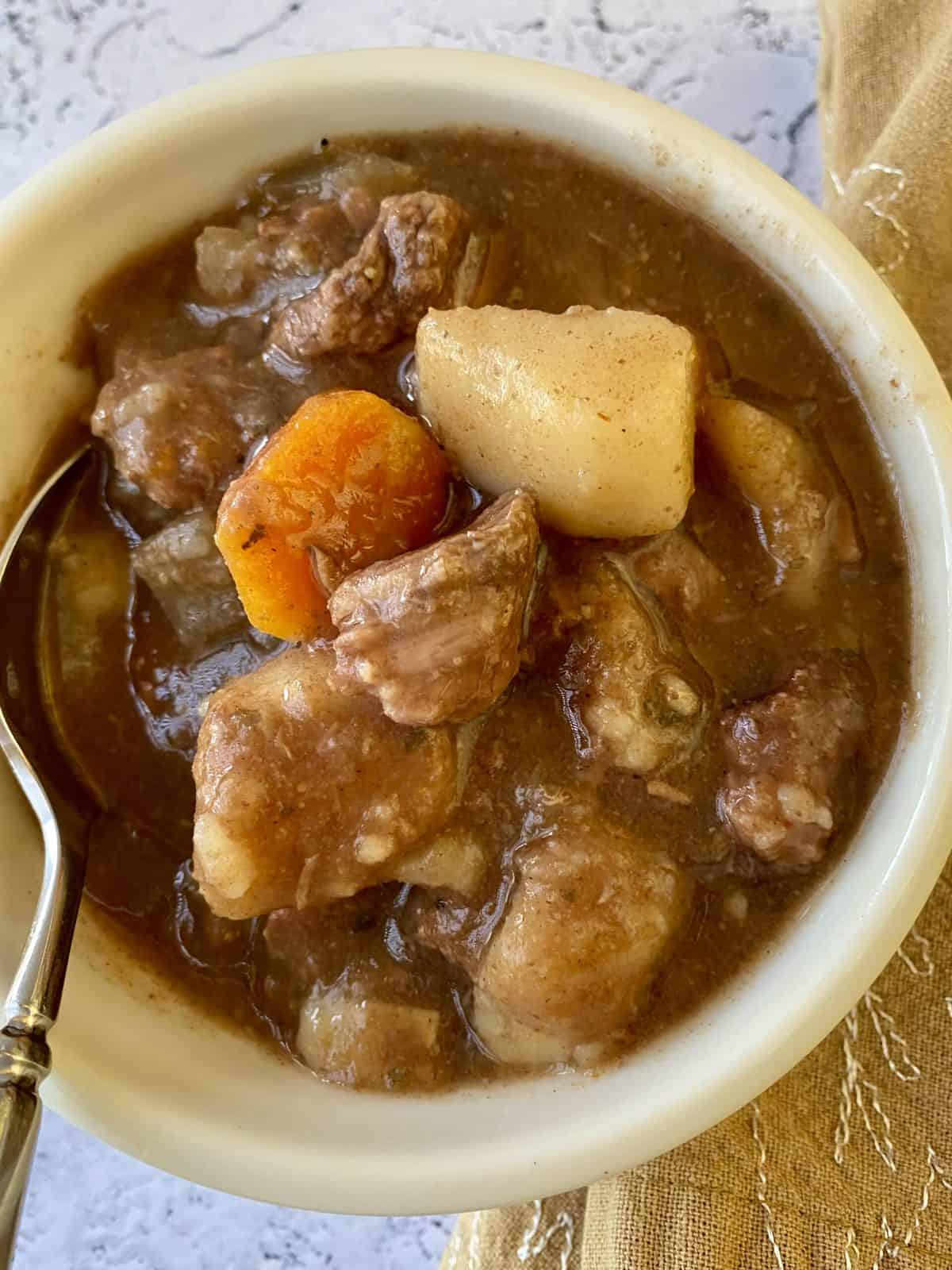 A small bowl full of St. Patrick's Day Stew with a spoon and napkin on the side.