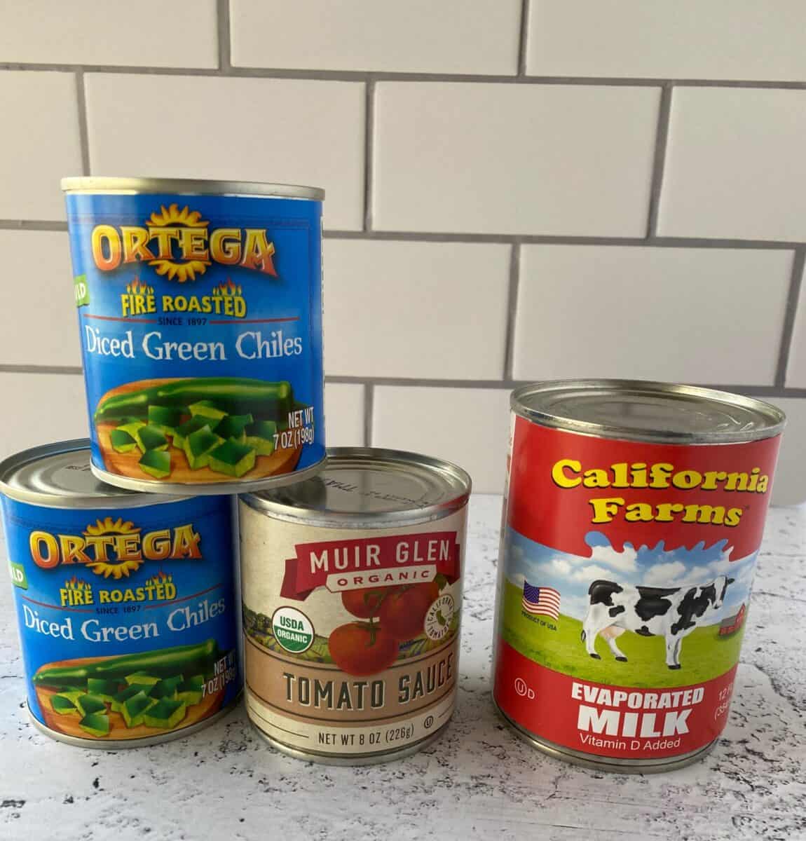 Canned ingredients for chili relleno casserole stacked on a counter.