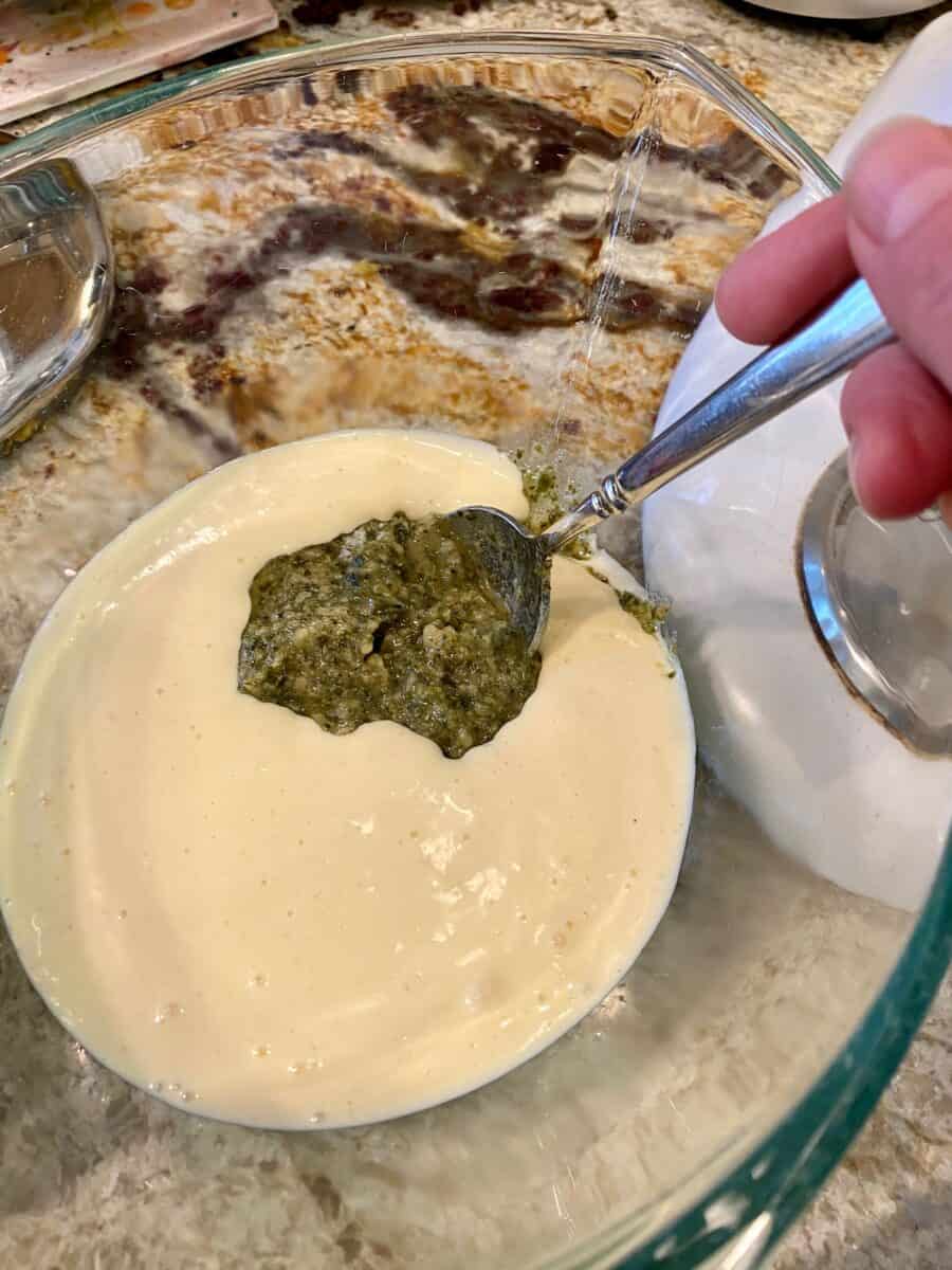 Raw batter with pesto being stirred into it.