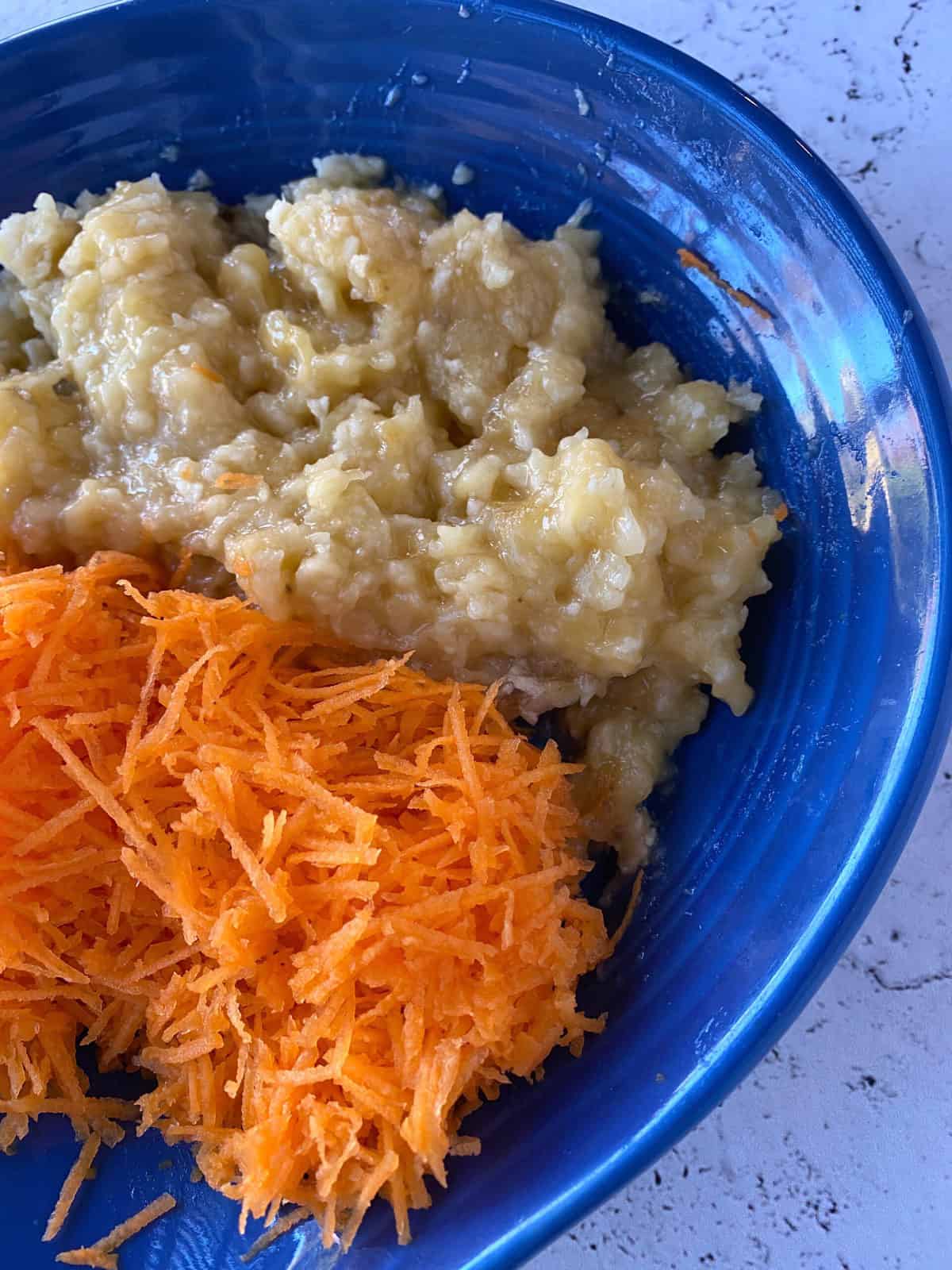 Shredded carrots and mashed bananas in a dish.