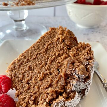 A slice of chocolate pound cake with raspberries on the side.