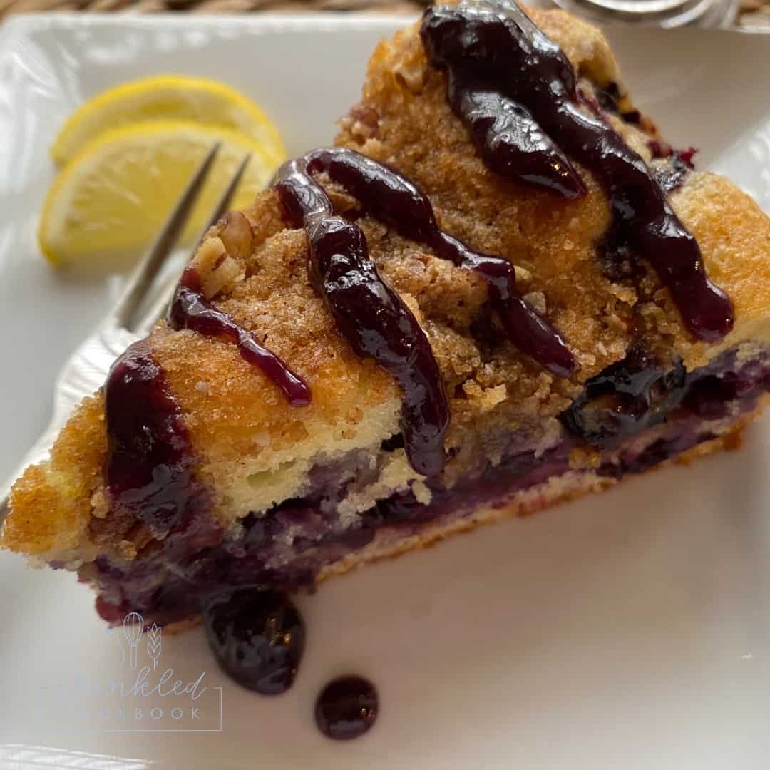 A wedge of blueberry cake on a plate. 