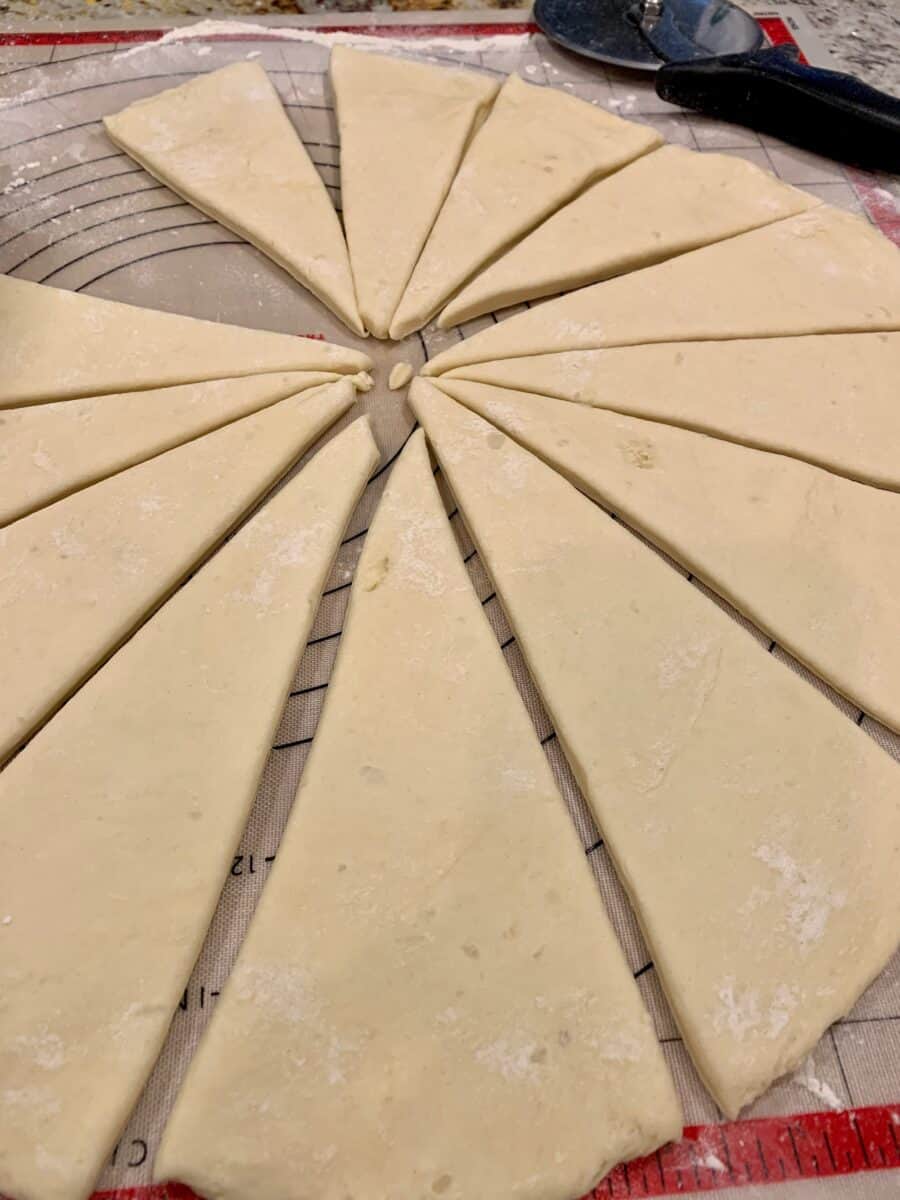 Classic Potato Roll dough, rolled out and sliced into wedges on a cutting mat.