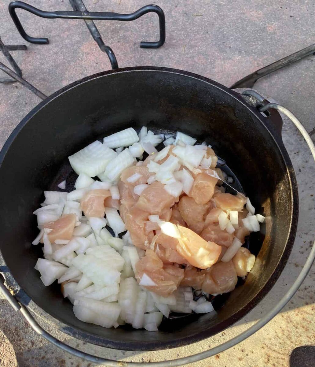 Diced chicken and chopped onions in a Dutch Oven.