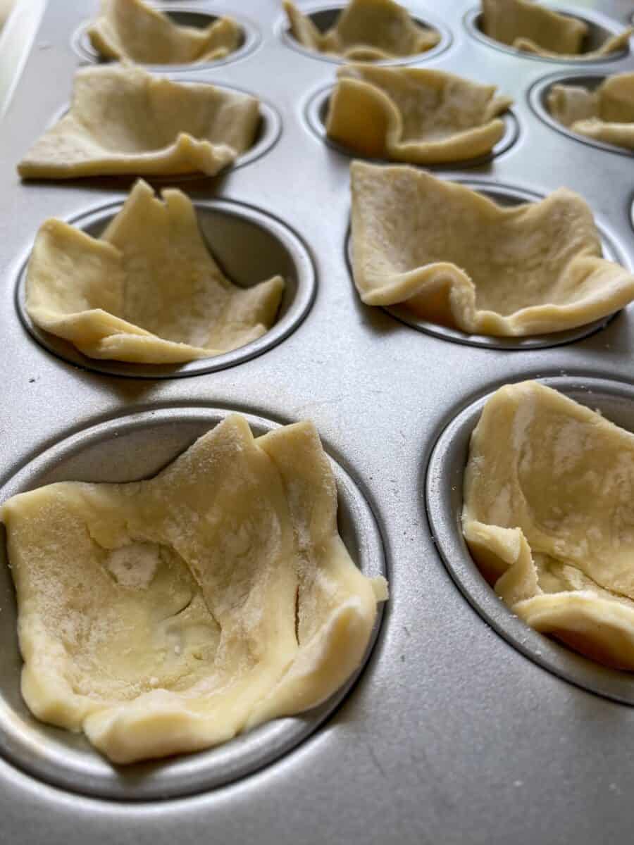 Puffed pastry dough, raw, placed into mini-muffin cups.