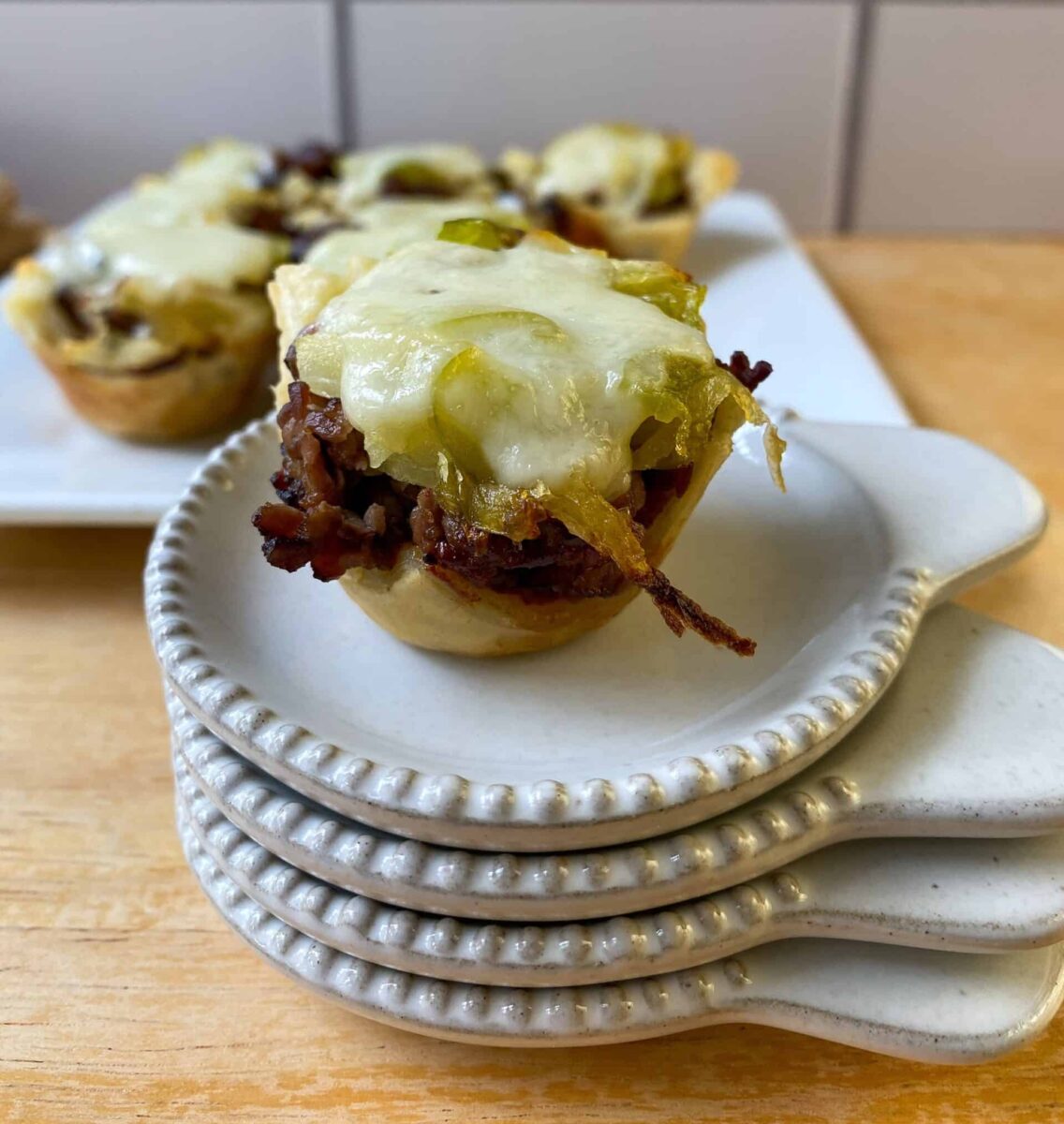 mini cheesesteak bite on a stack of tasting plates.