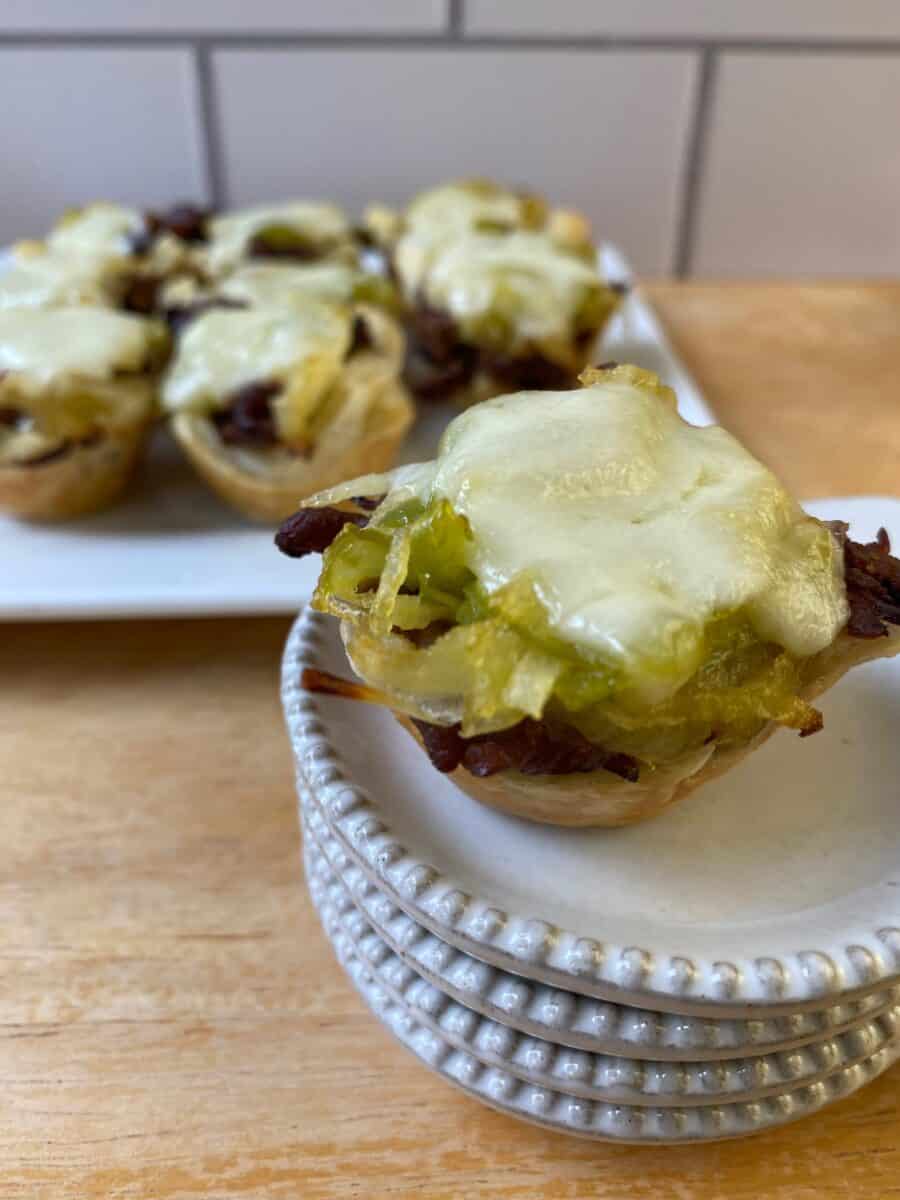 Philly Cheesesteak bite on a small stack of dishes with the serving plate in the background.