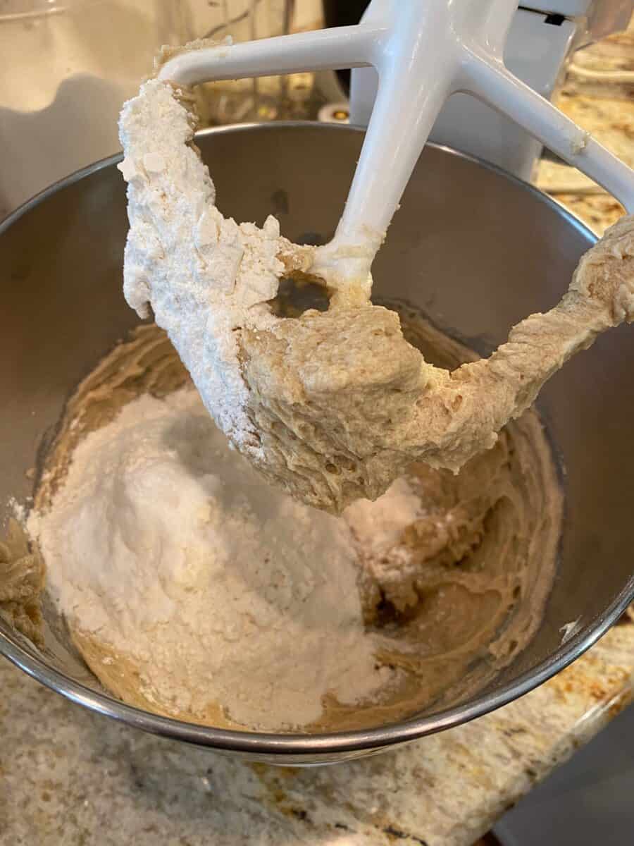 Dry ingredients with wet ingredients in a mixing bowl with the mixing paddle above the dough.