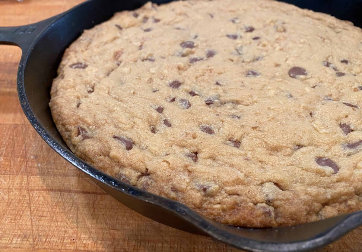 Baked chocolate chip cookie bar in a cast iron skillet.