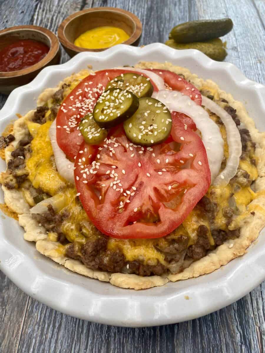 Cheeseburger pie in a pie plate with ketchup and mustard in small dishes on the side. 