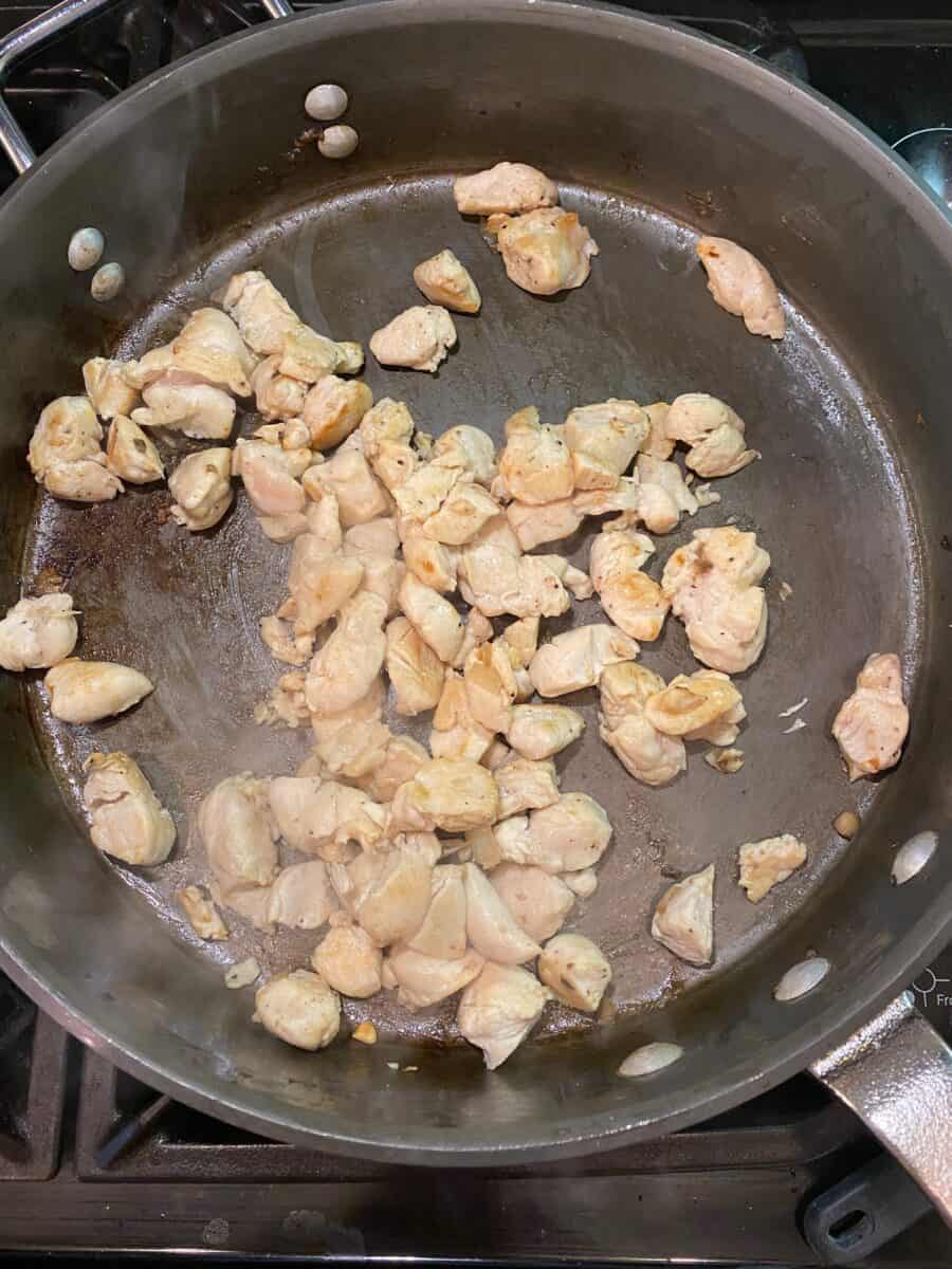 Diced chicken, cooked and in a skillet on the stove.