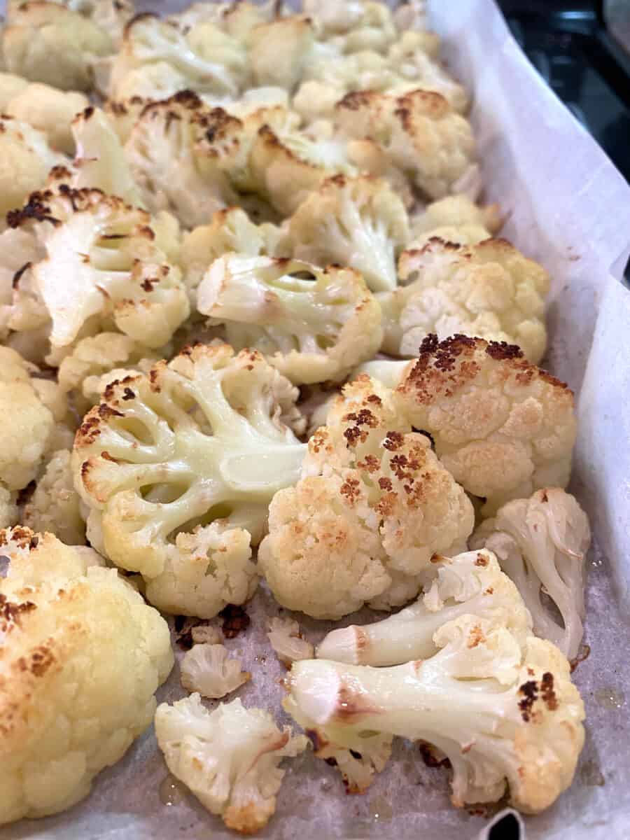 Oven-roasted cauliflower on a baking pan lined with parchment paper.