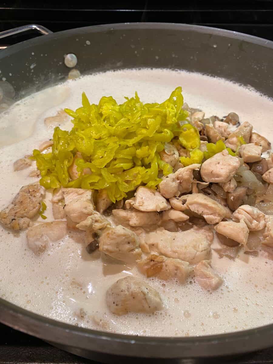 Alfredo sauce, chicken, mushrooms, onions and pepperoncinis in a skillet.