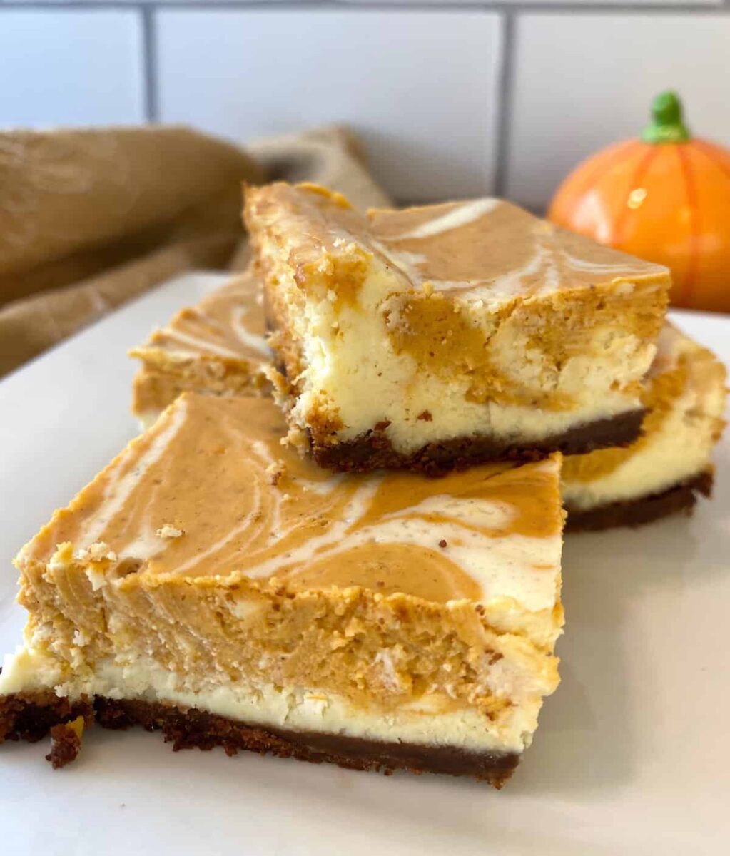 Three baked cheesecake bars stacked on a plate.