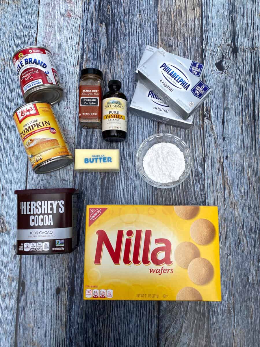 Ingredients for marbled pumpkin cheesecake bars, spread out on a wooden board.