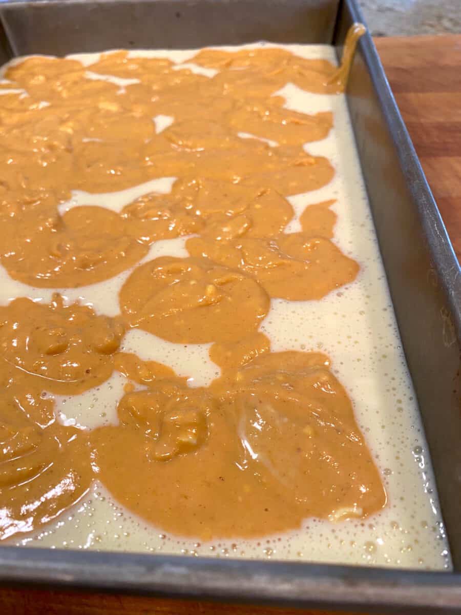 Uncooked batter for pumpkin cheesecake bars in a baking pan.