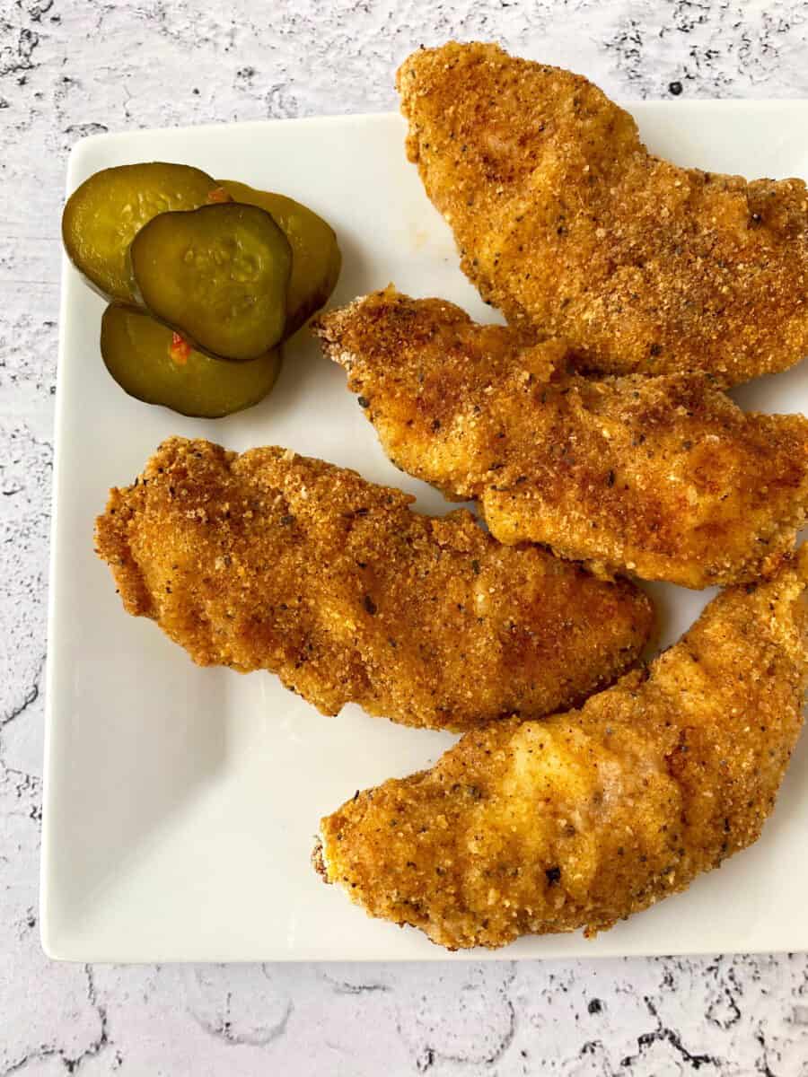 Four chicken strips on a serving plate