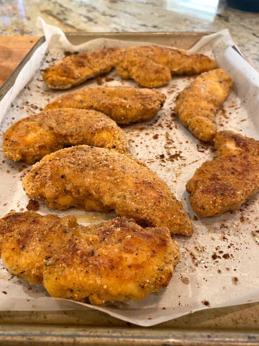 Baked chicken on a piece of parchment paper on a baking sheet