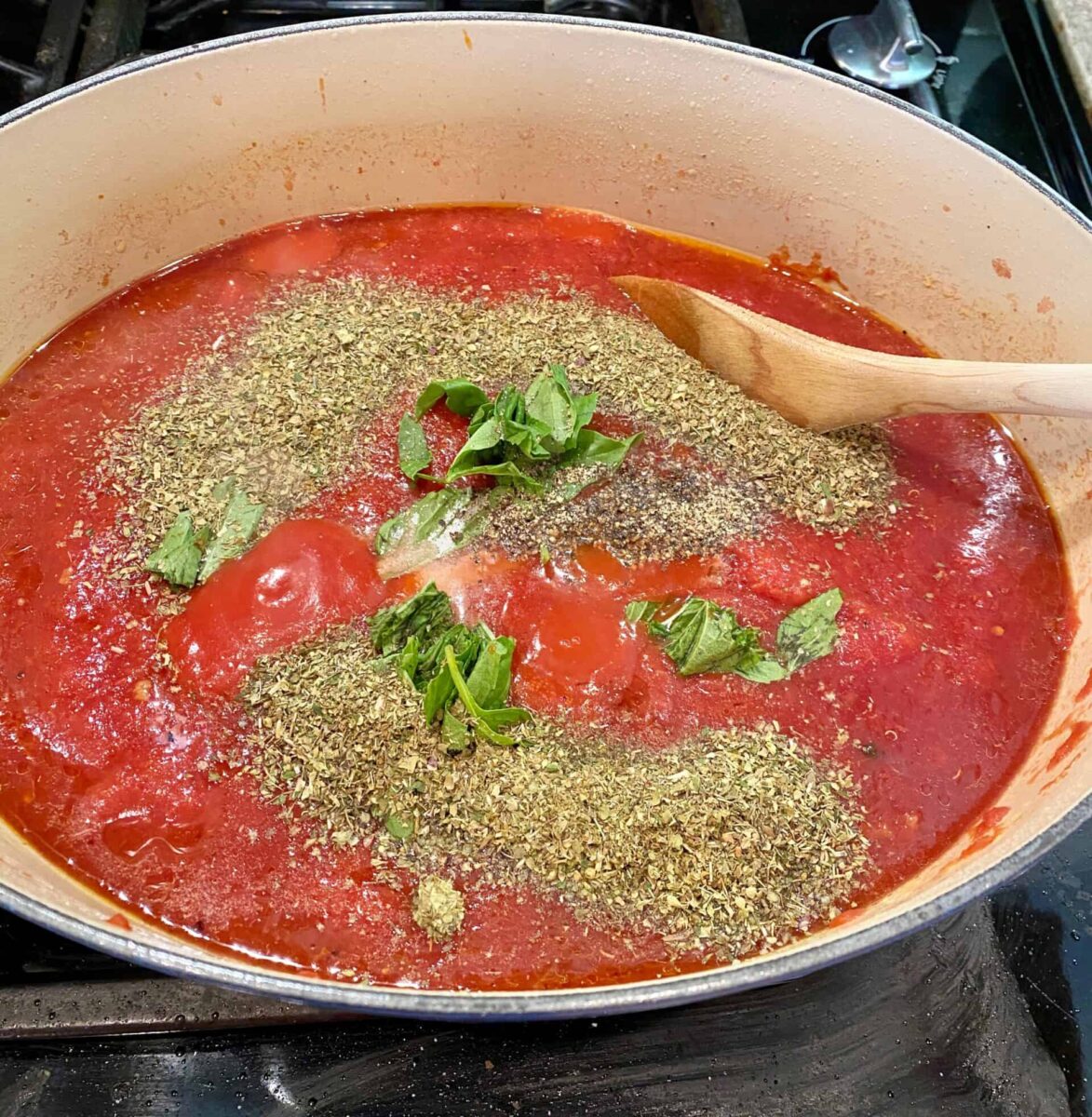 Spaghetti sauce, spices and fresh basil simmering in a pot on the stove