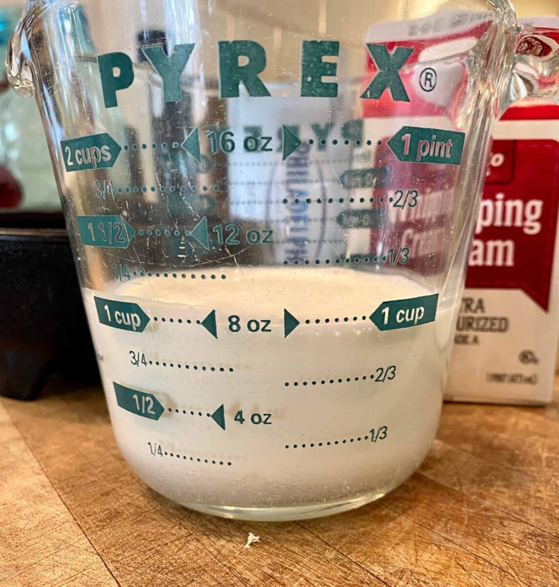 One cup of whipping cream in a glass measuring cup