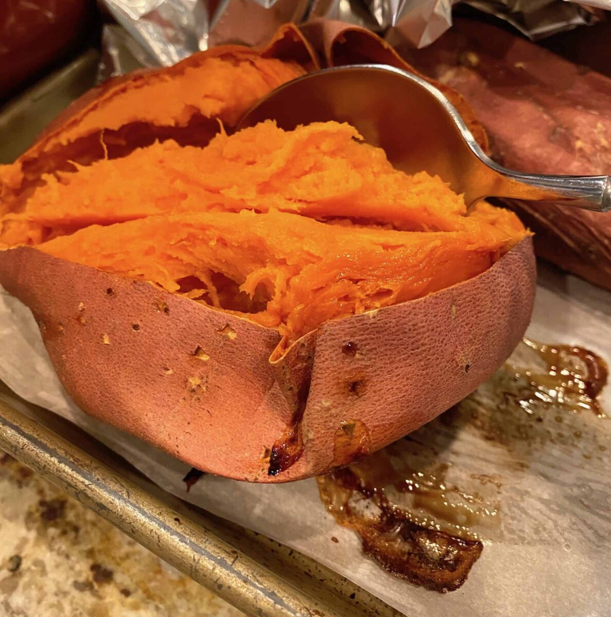 Baked sweet potato sliced open with a spoon scooping out the filling