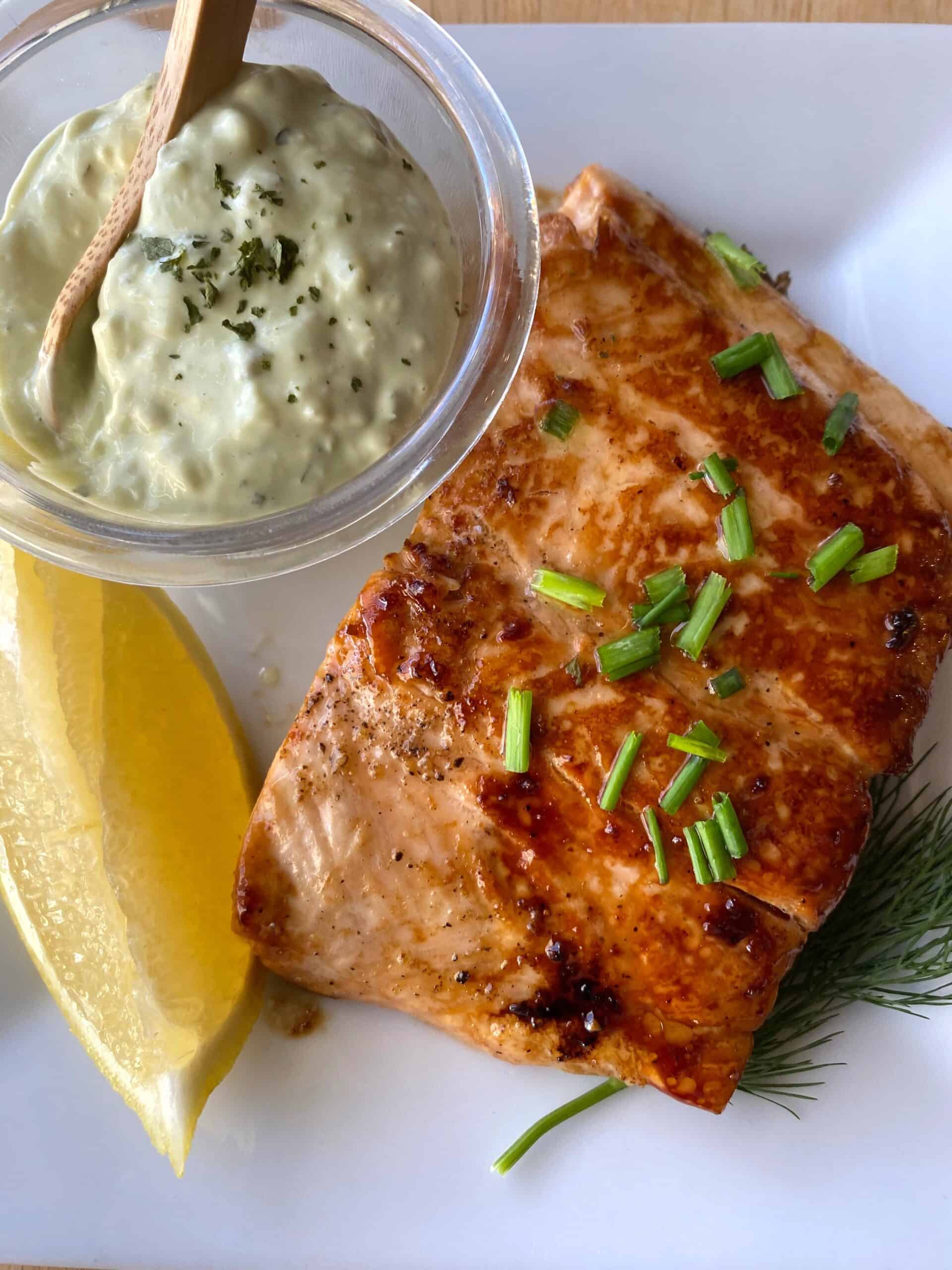 Salmon on a dish with a wedge of lemon and a small dish of tarter sauce