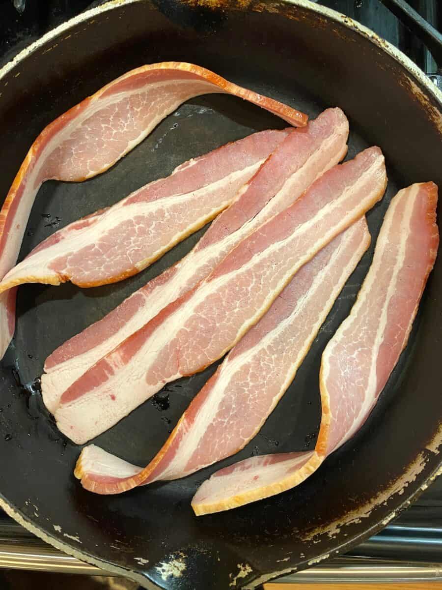 Six slices of bacon in a cast iron skillet