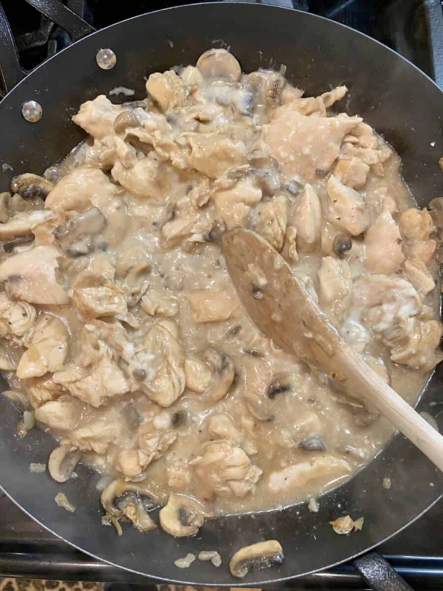 Chicken stroganoff with mushrooms simmering in a skillet on the stove