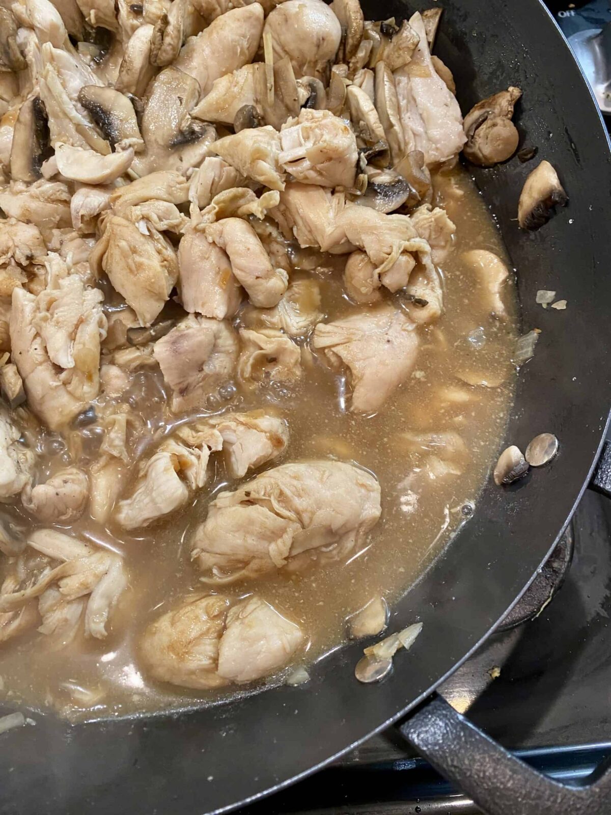 Simmering sauce with chicken in a skillet on the stove