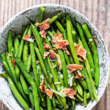 Green beans in a bowl with bacon on top