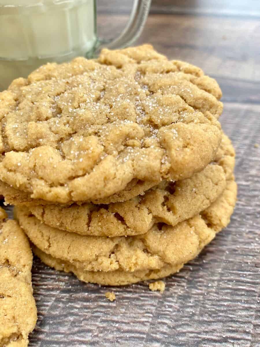 A stack of peanut butter cookies next to a glass of milk.