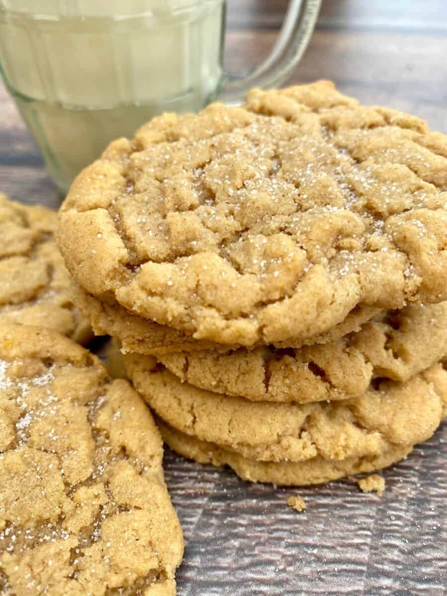 A short stack of peanut butter cookies next to a small glass of milk.