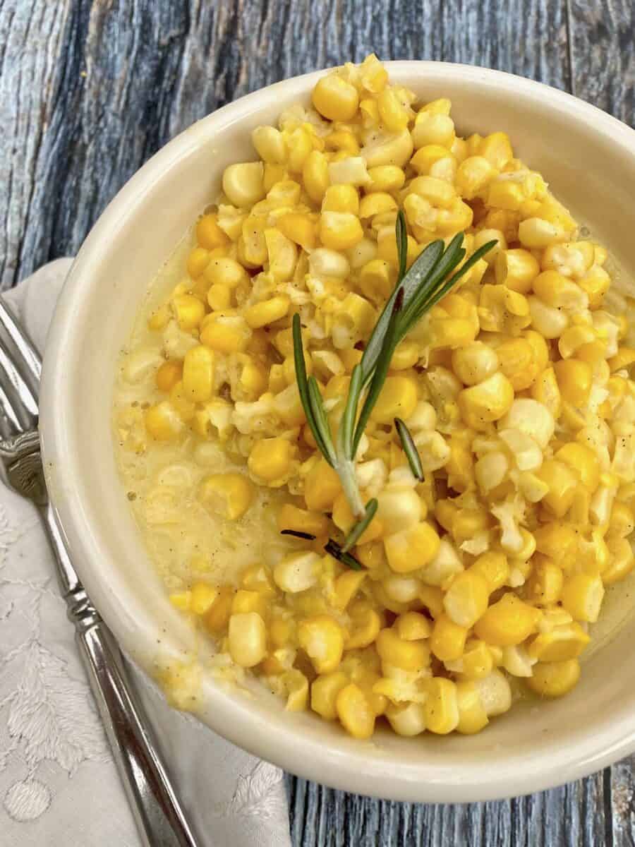 Creamed corn in a small bowl with a fork and napkin on the side. 