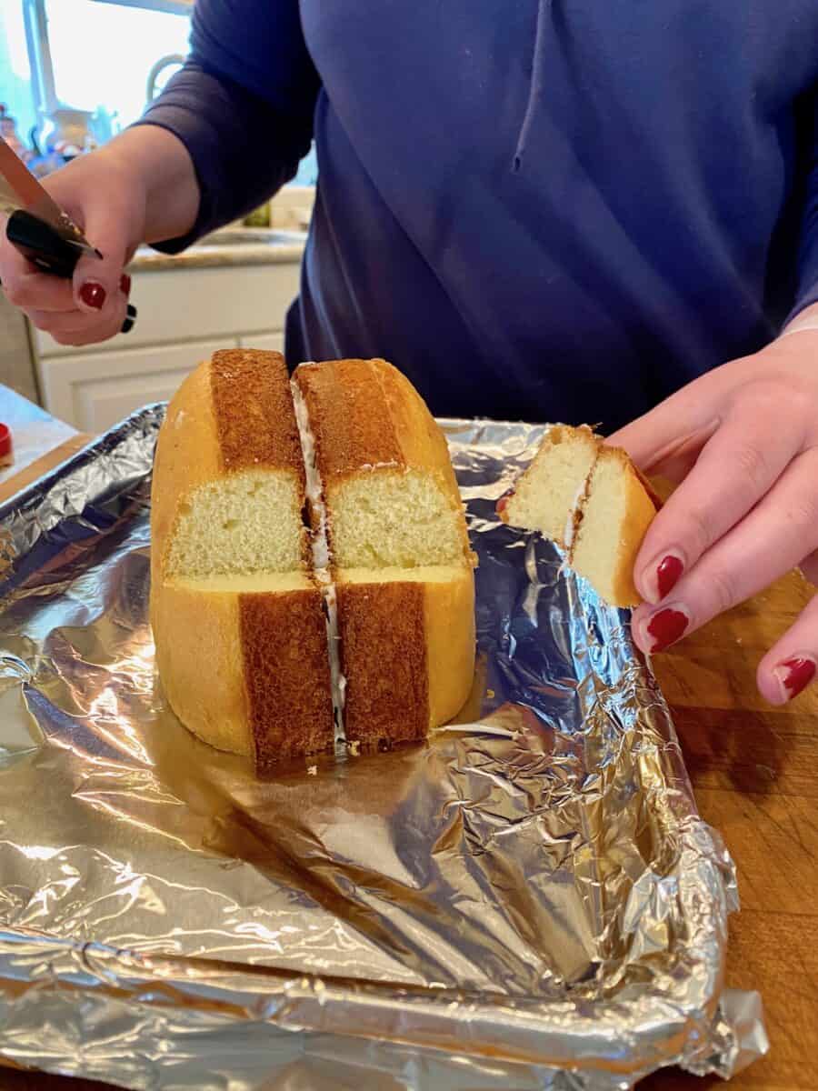 A wedge of cake cut from two baked cake rounds placed on a foil lined baking sheet. 