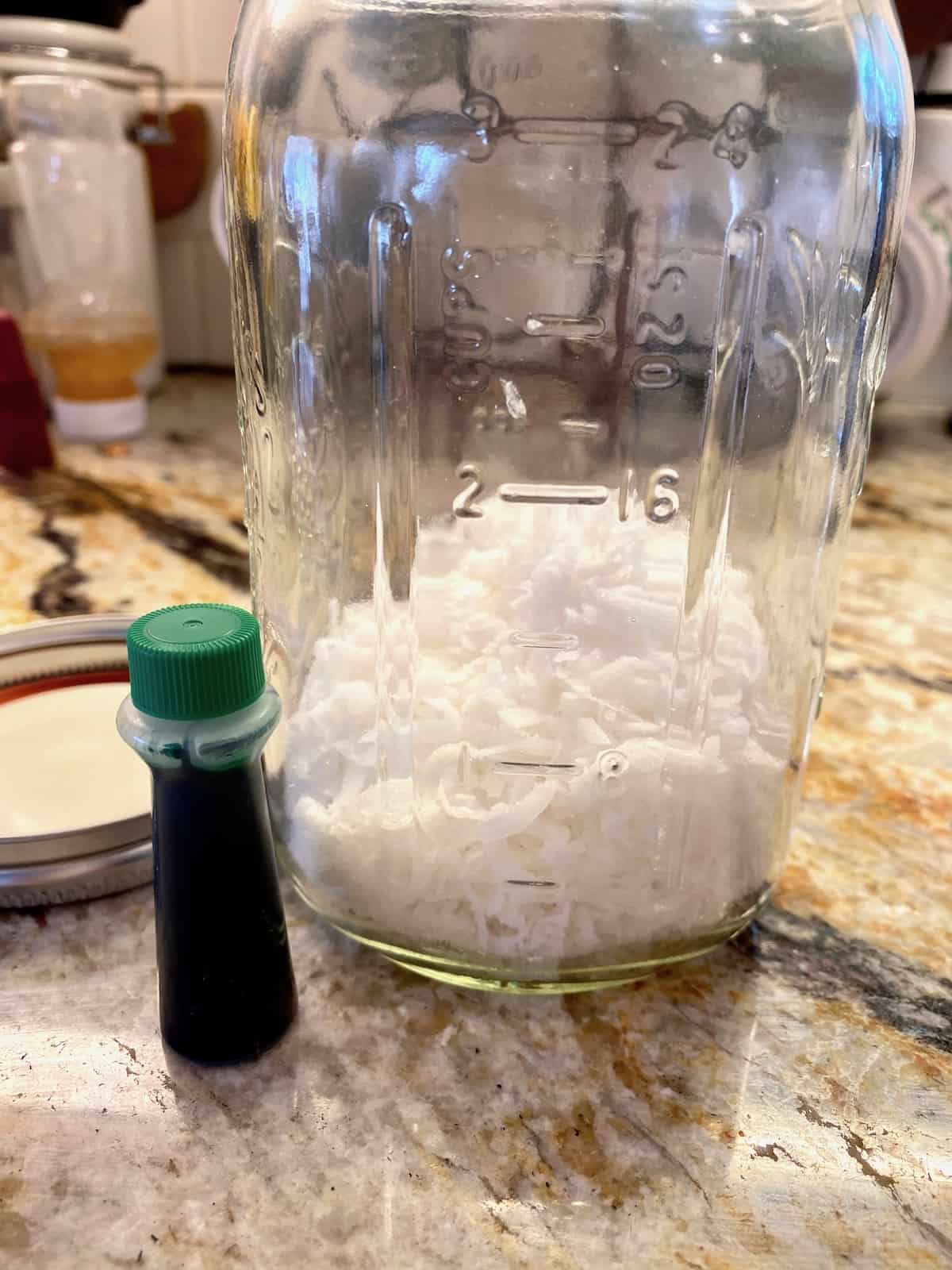 Coconut in a jar with a small container of green food coloring on the side.