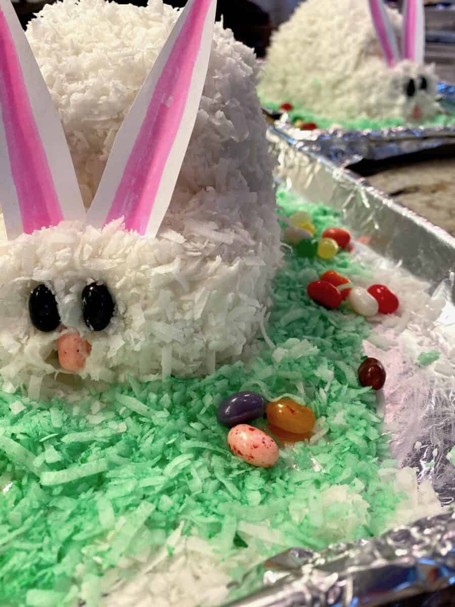 Two baked bunny cakes on baking sheets with coconut.