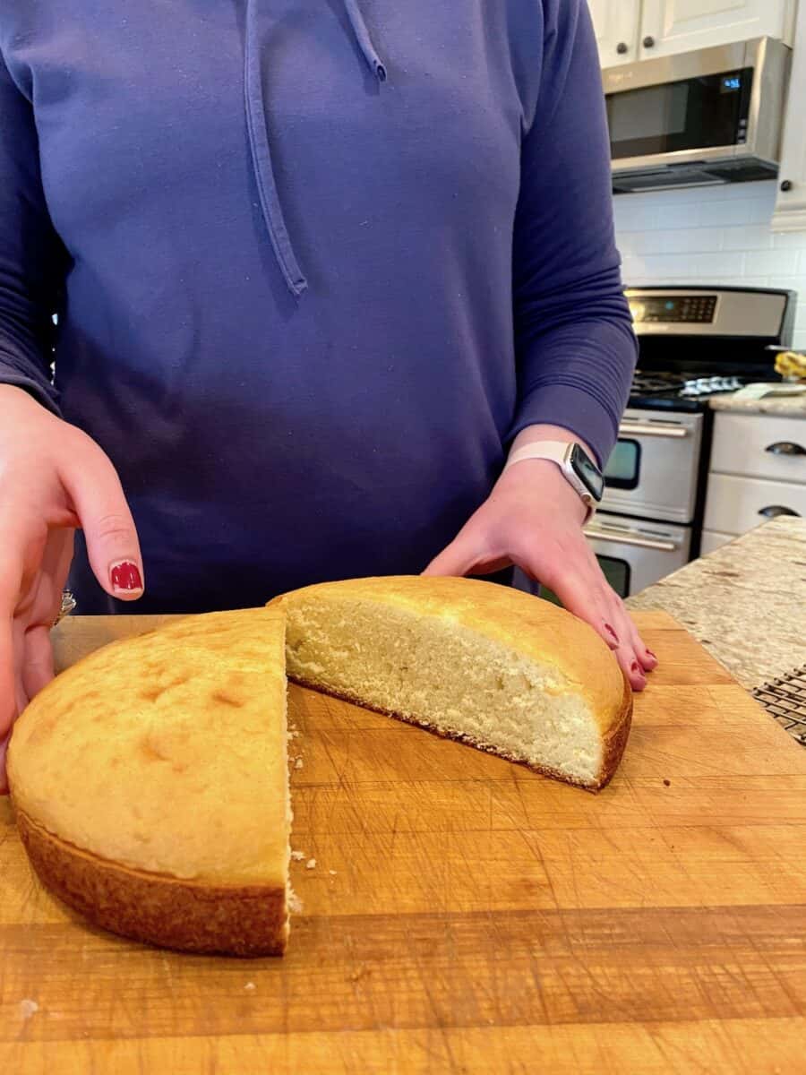 Cake round cut in half on a cutting board.