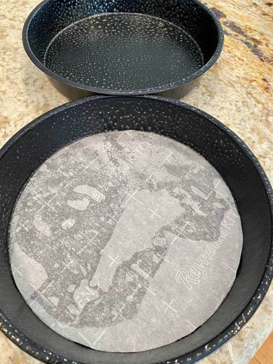 Two round baking pans, one lined with parchment paper. 