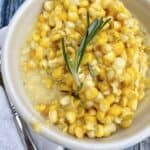 A small bowl of creamed corn with a knife on the side.