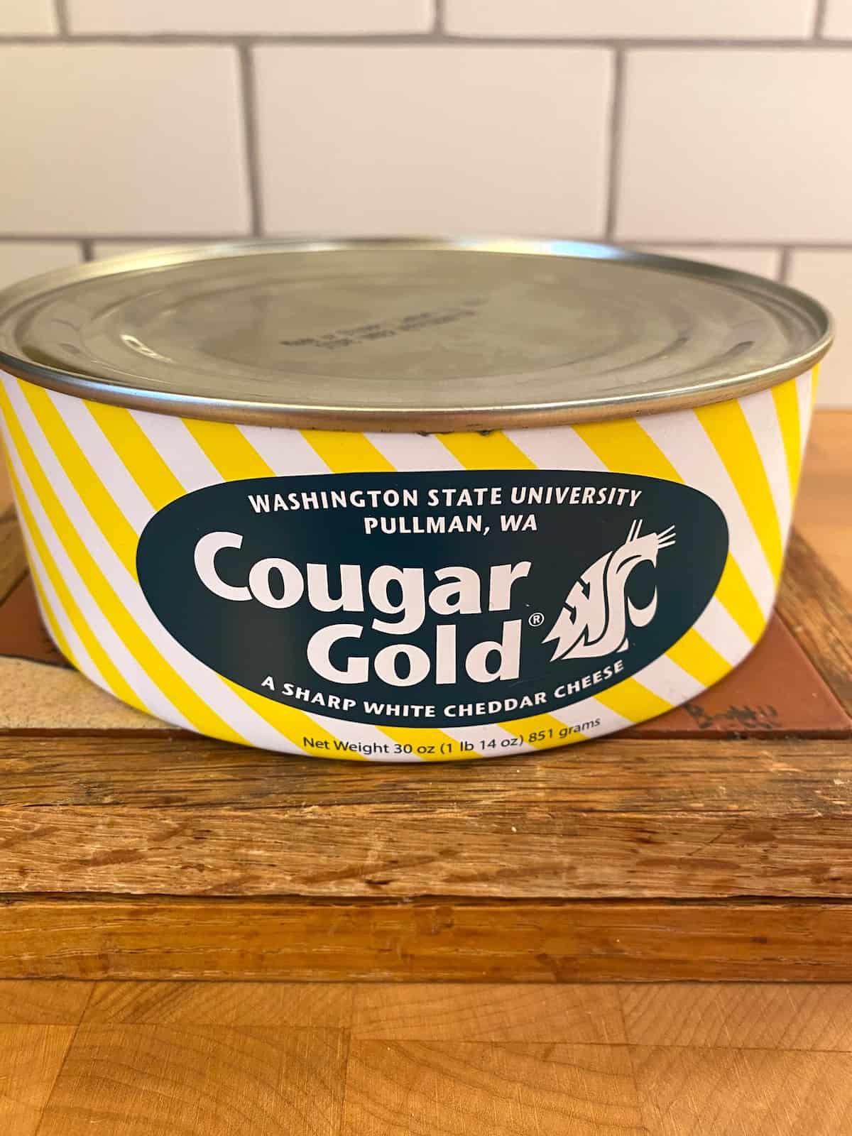 One can of cougar gold cheese on a cutting board.