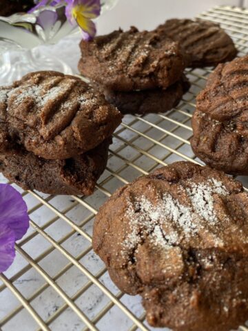 Molasses Snaps cookies on a cooling rack with a pansy on the side.