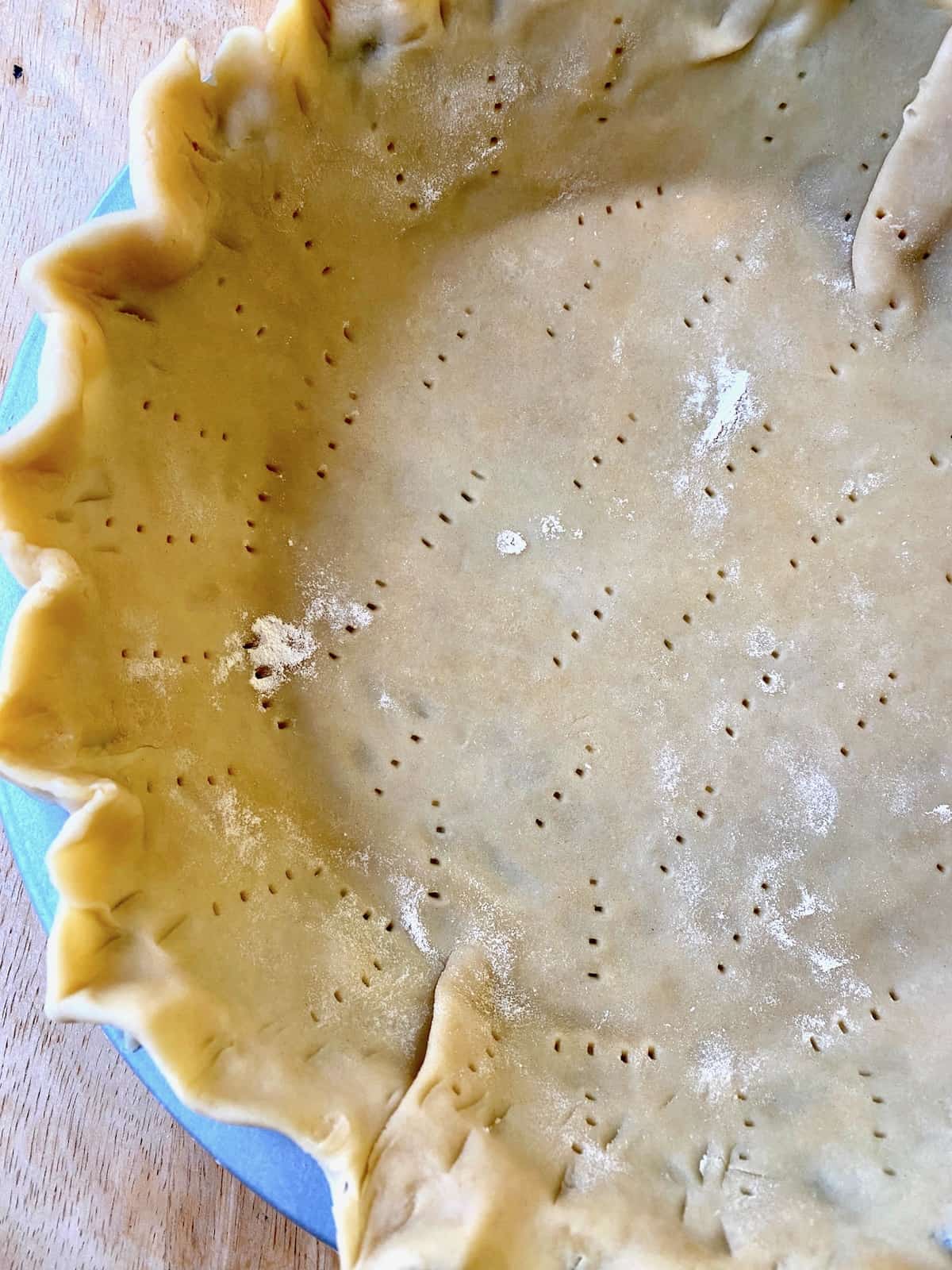 Quiche crust, unbaked with small holes from a fork.