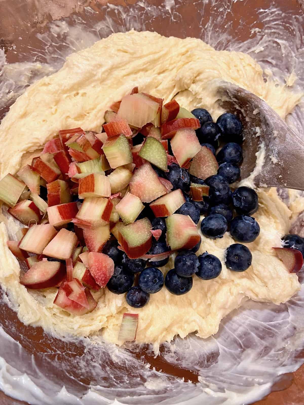 Rhubarb and blueberries in the muffin batter in a bowl.