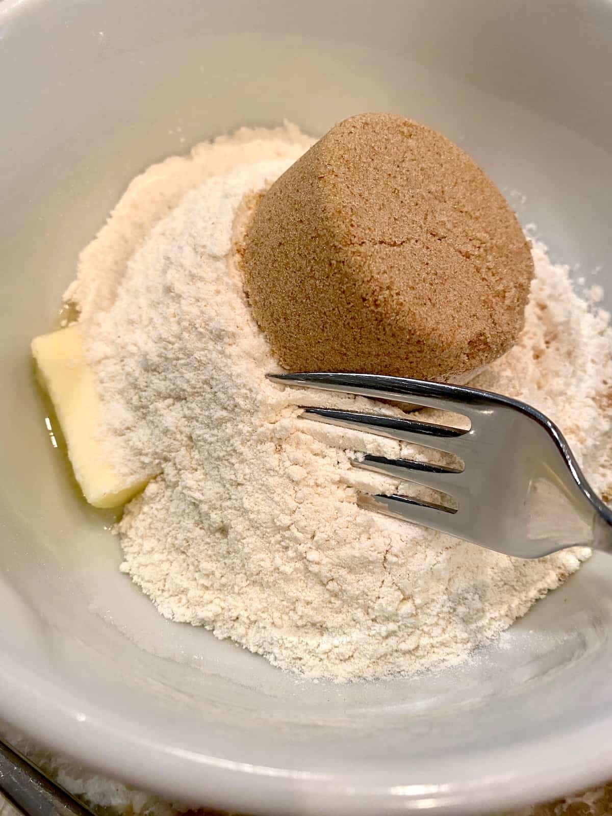 A fork blending together brown sugar, butter and flour.