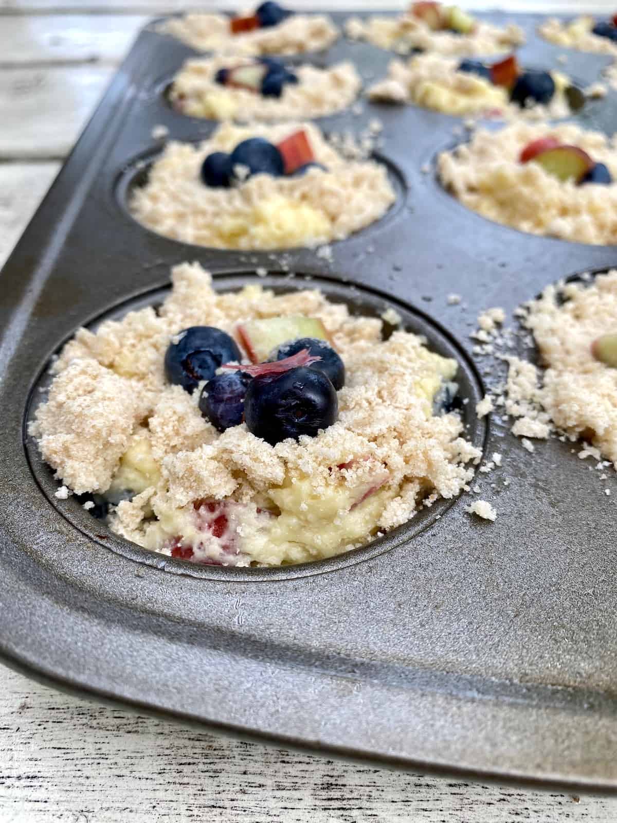 Unbaked muffins with topping, in a muffin pan.