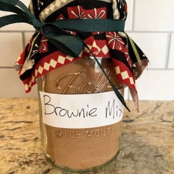 A jar of brownie mix with a ribbon and fabric on the top of the jar.