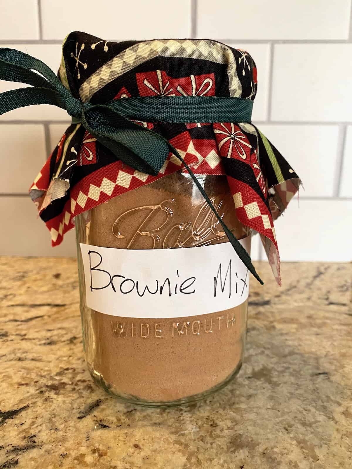 A jar of brownie mix with a ribbon and fabric on the top of the jar. 