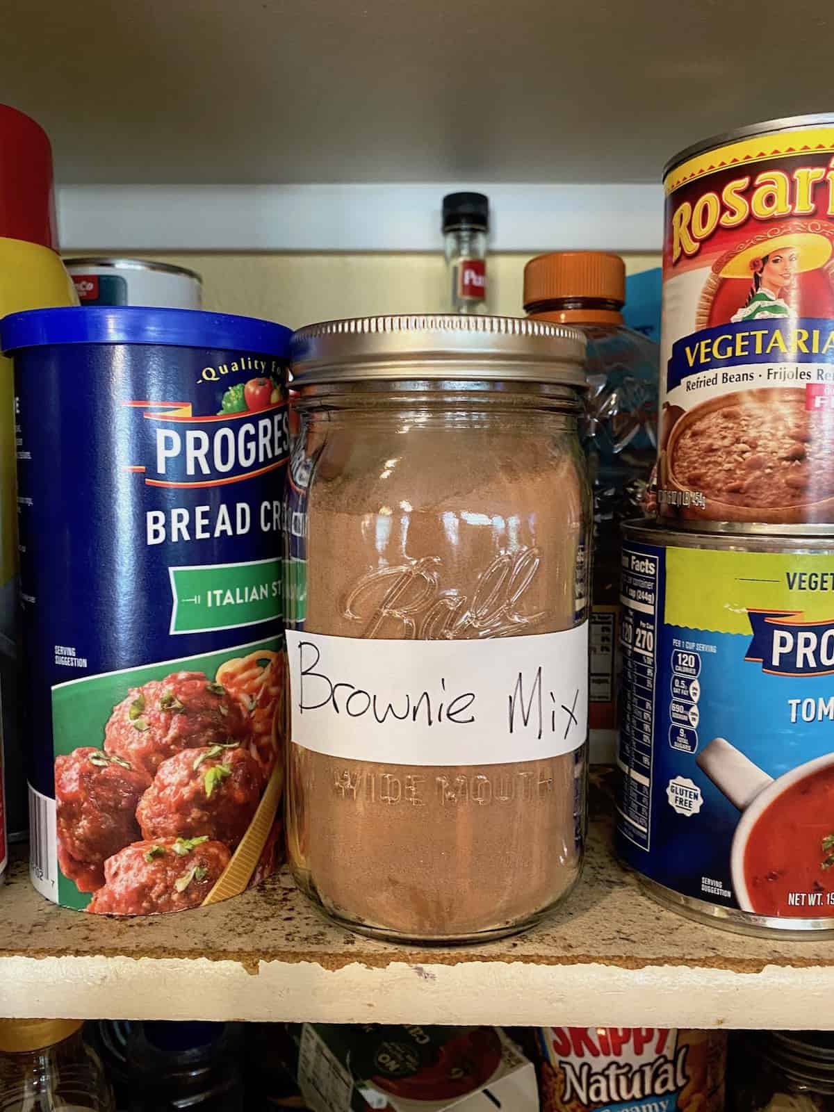 A jar of brownie mix on a pantry shelf.