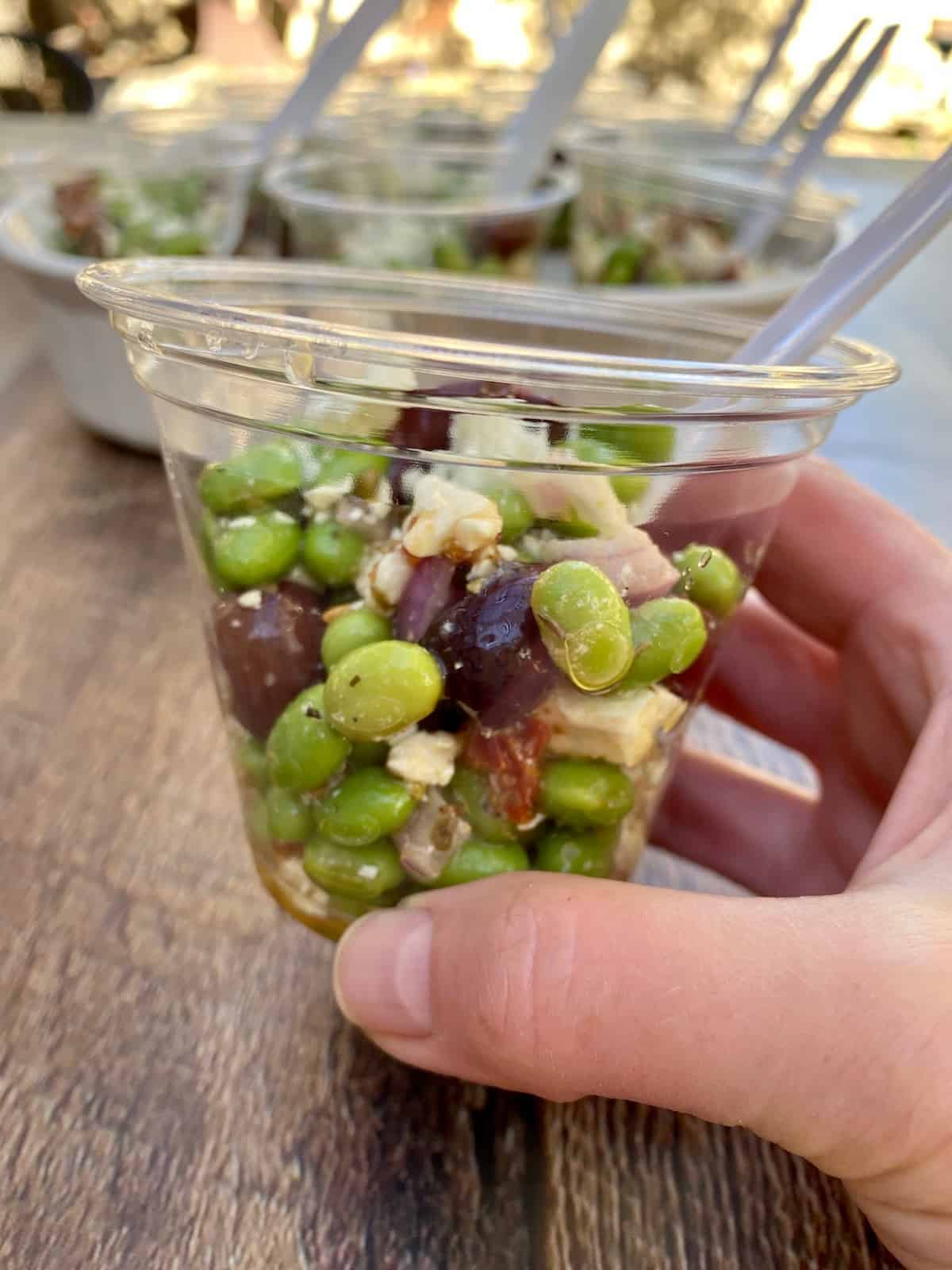 A single serving of edamame salad in a clear cup.